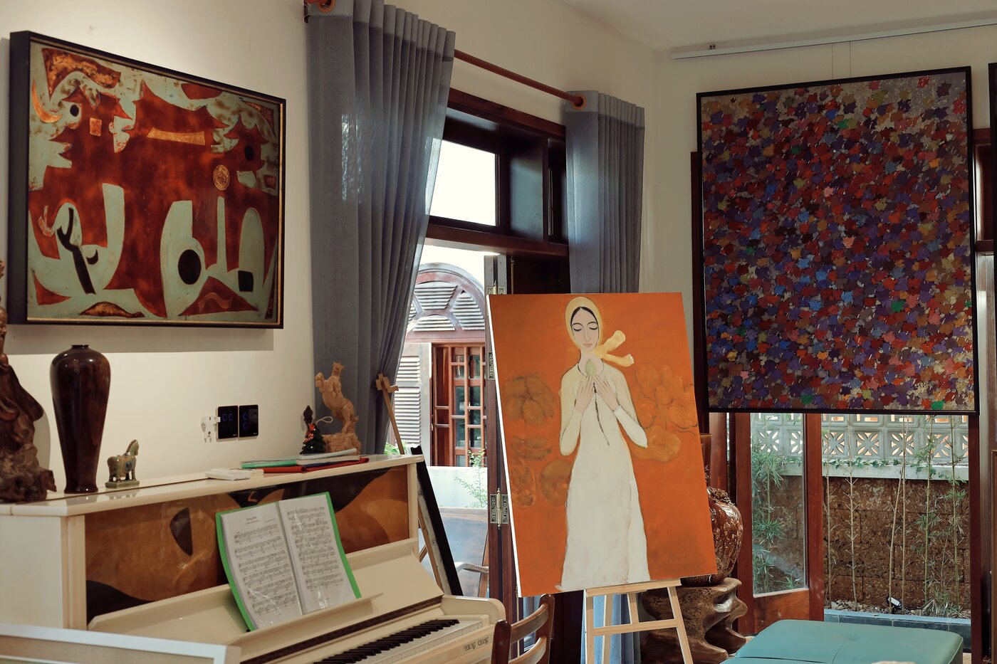 Góc dương cầm tại Nhung Art Space với tranh trừu tượng, tranh thiếu nữ áo trắng, đàn piano và khung cửa vòm